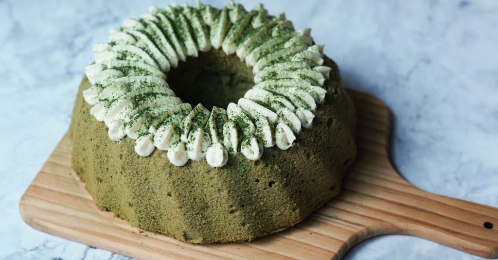 Delicious matcha bundt cake topped with whipped cream on a rustic board.